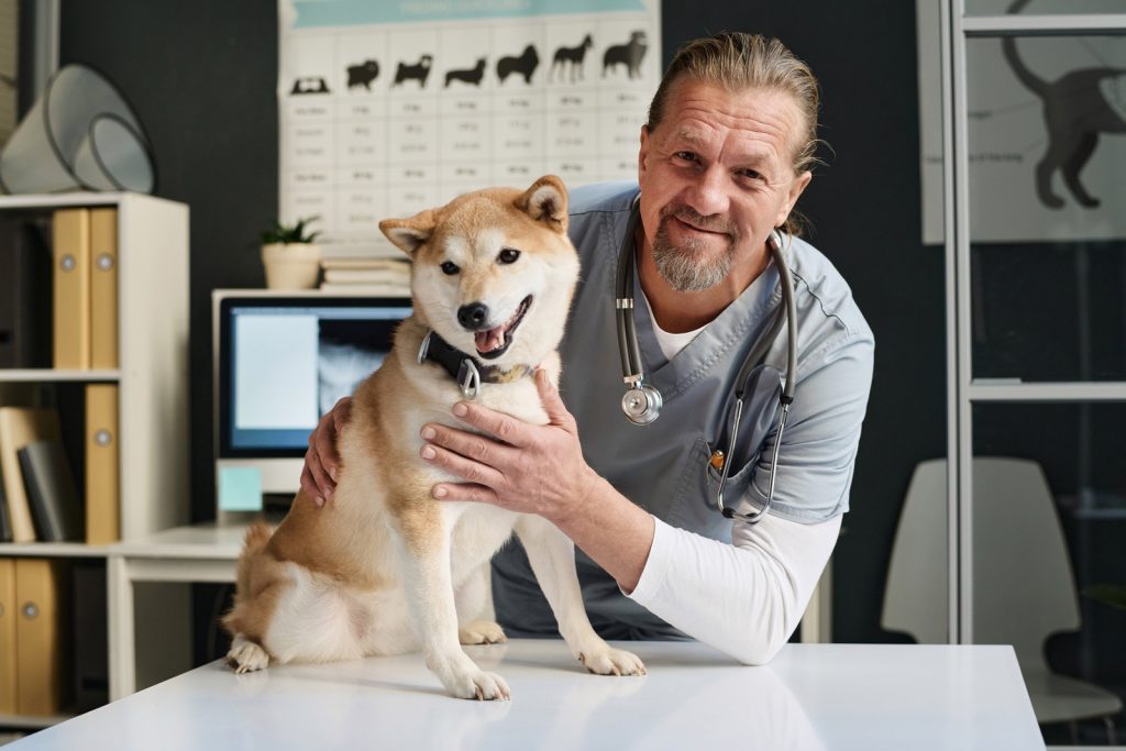 veterinarian and his canine patient posing together in vet office
